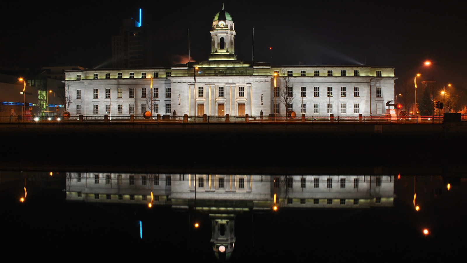 Vista noturna da Prefeitura de Cork refletida no rio Lee