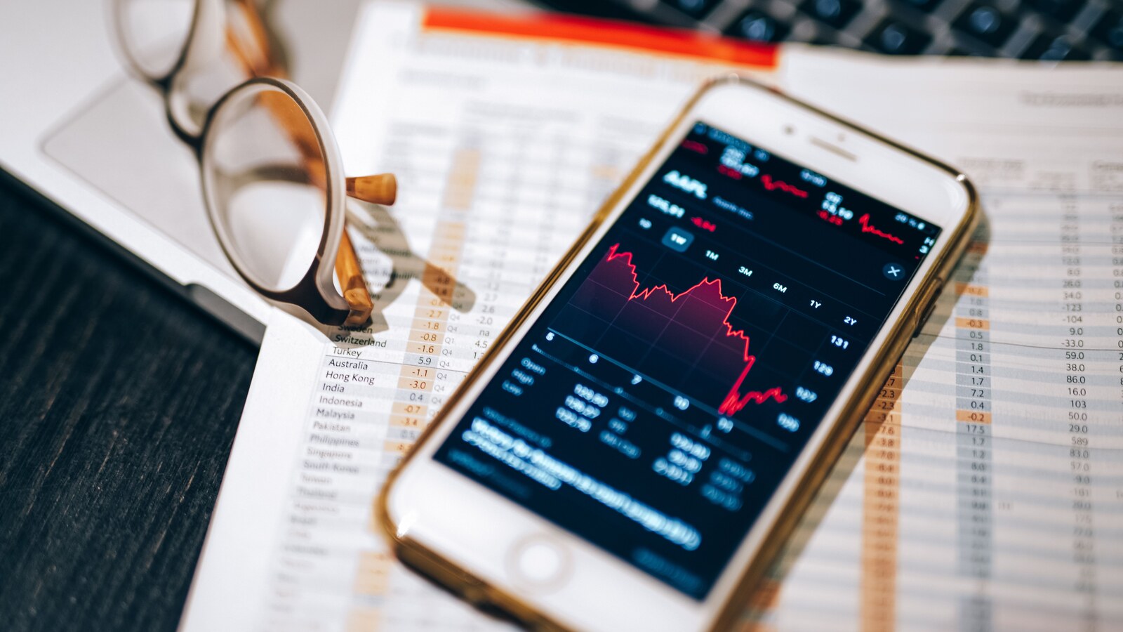 Pessoa acompanha gráfico de investimento em um telefone celular