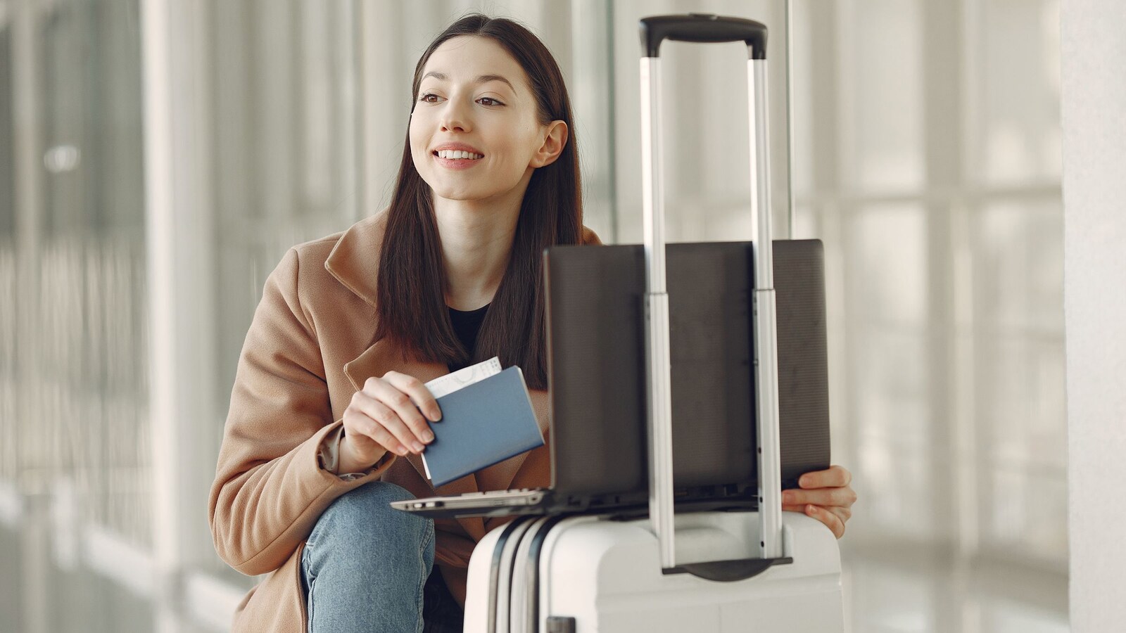 Viajante com passaporte, computador e bagagem em um aeroporto